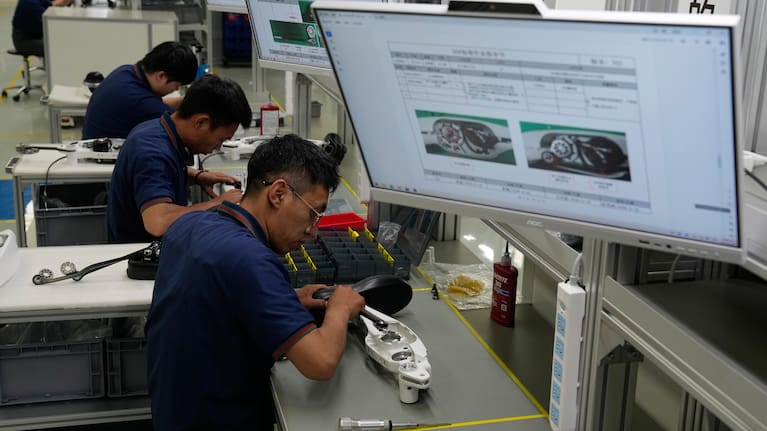 Workers assemble robot leg components.