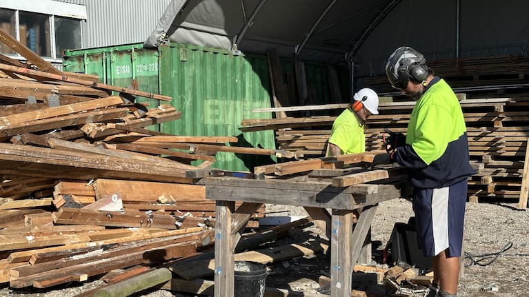 Workers at Levela Yard remove nails from the timber of flood-damaged homes.