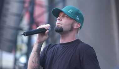 Fred Durst looking solemn on stage in a green cap