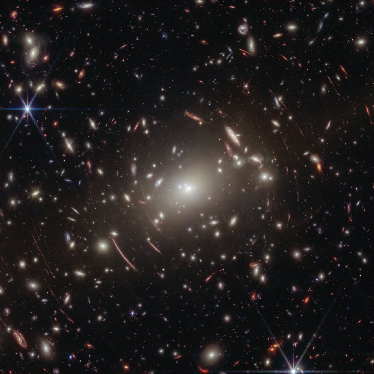 A view of lots of gravitationally lensed galaxies against the dark background of space.