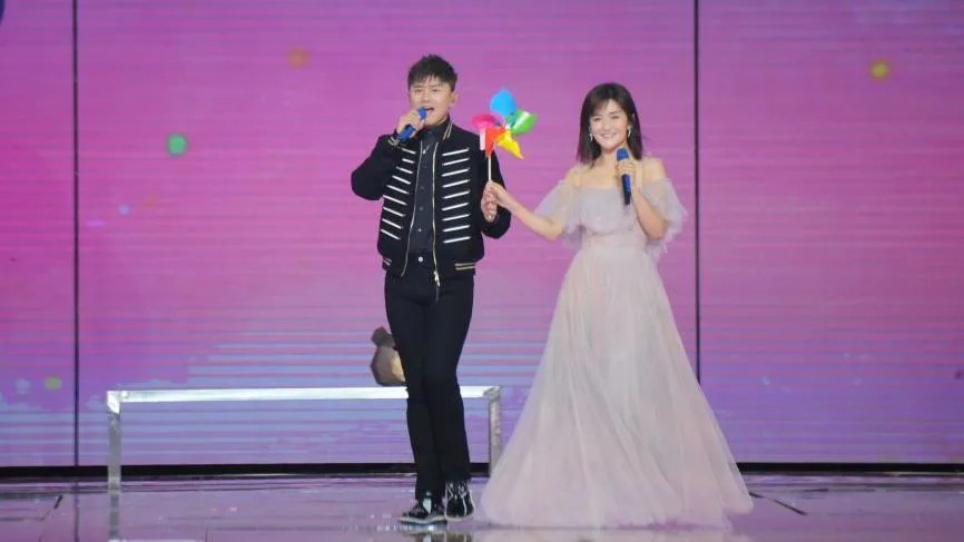 Zhang Jie and Xie Na holding hands as they perform on a stage