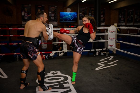 Instructor Sarkis Doueihi holding pads for Olaya during training.