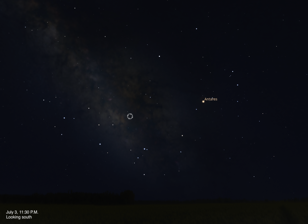 A simulated night sky looking south on July 3, 2026 at 11:30 P.M. A small circular target indicator marks an unnamed object embedded in the faint glow of the Milky Way near the center of the frame. The bright orange-red star Antares is visible to the right, and the dense star clouds of the Milky Way stretch across the left side of the image.