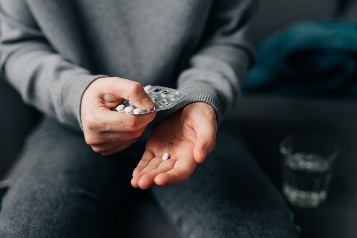 Female hands with pills on background of water glass with effervescent tablet