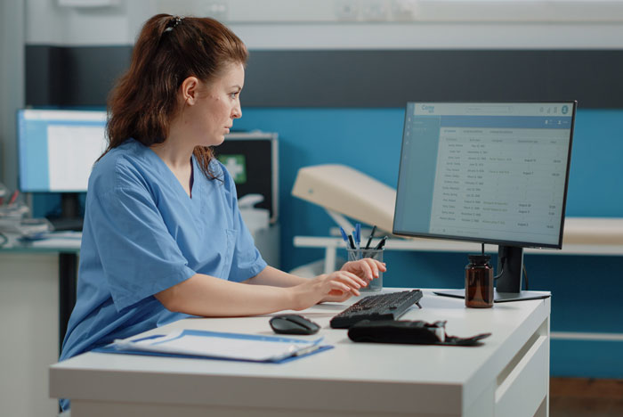 A medical worker typing on a computer, sharing facts about the hidden side of hospitals.