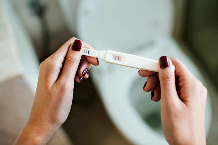 A patient holding a positive pregnancy test, failing to outsmart their doctors about their condition.