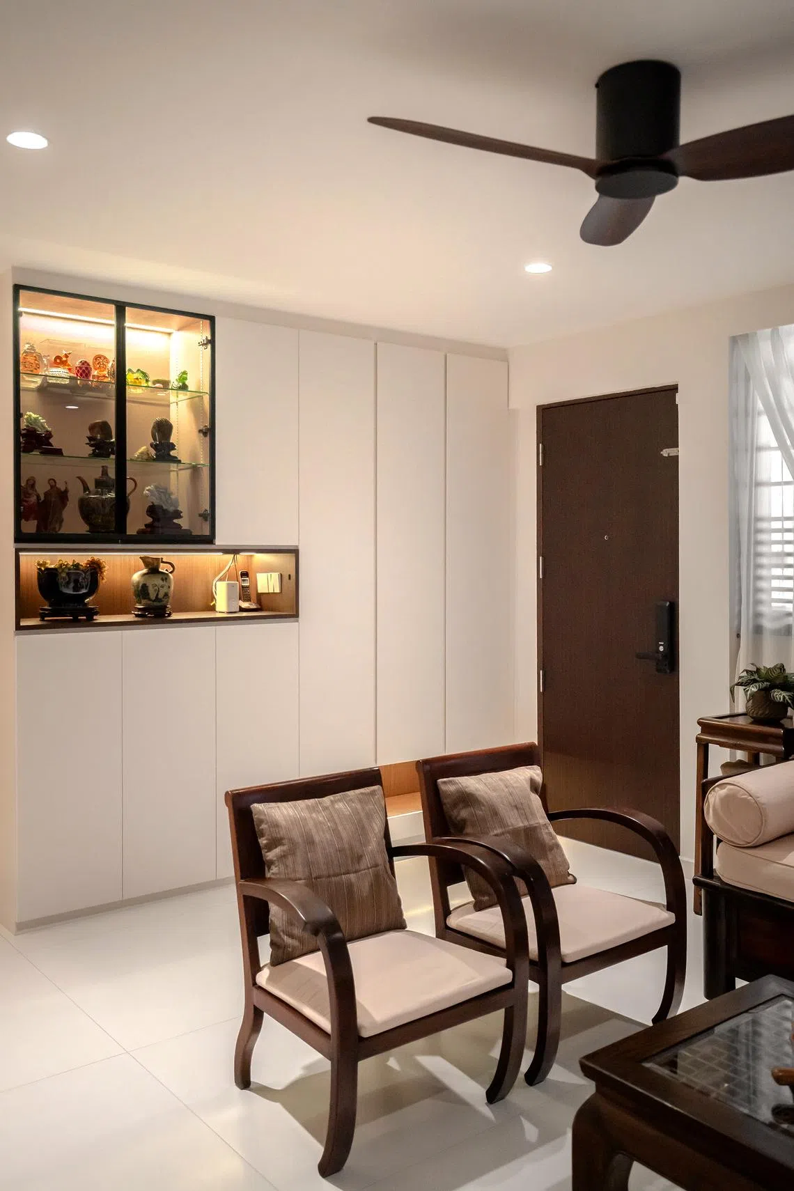A glass-fronted cabinet displays vases, figurines and jade carvings from the owner’s travels. 