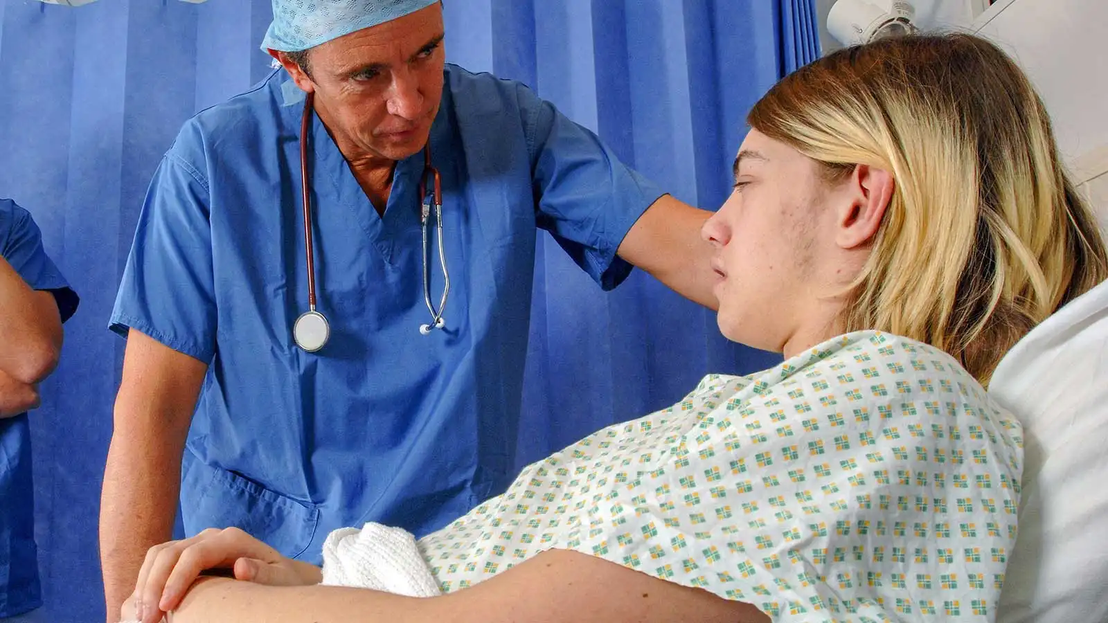 A doctor in hospital bedside consultation with a young male patient.
