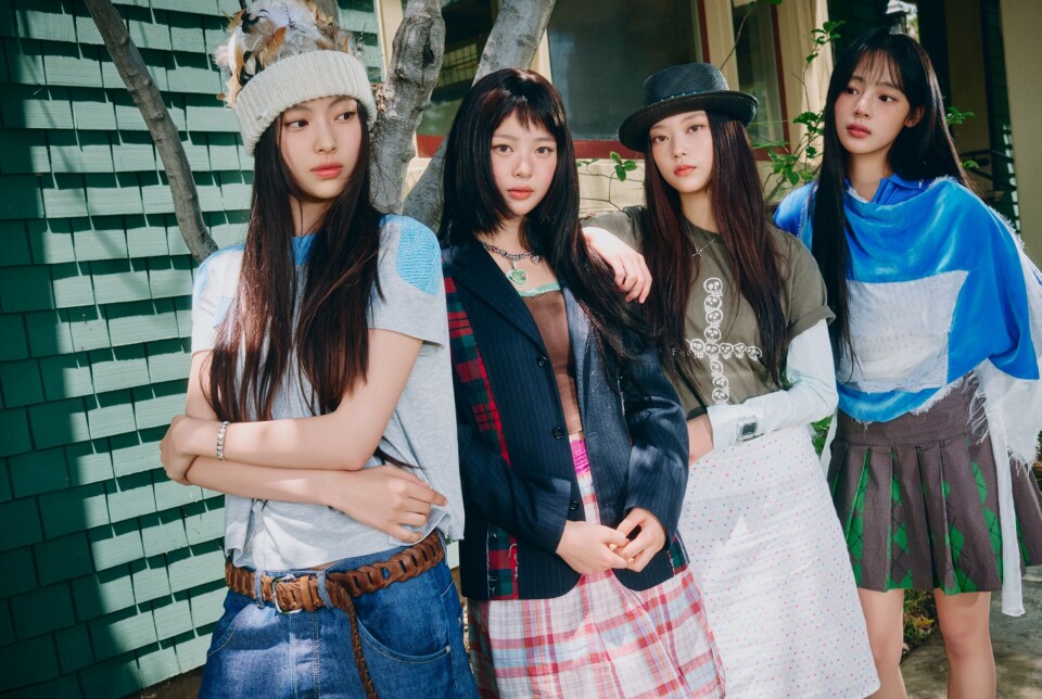 Four women posing in casual outfits beside a green tiled wall.