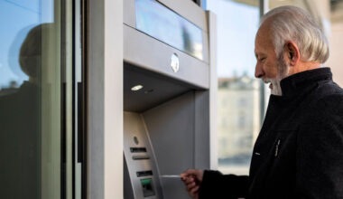 An older man who is using his credit card at an atm.