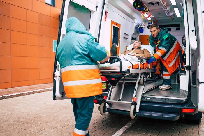 Paramedics helping a patient get into an ambulance for medical industry care.