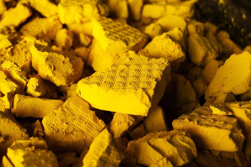 Close-up of yellow uranium pieces, broken and scattered on a surface.
