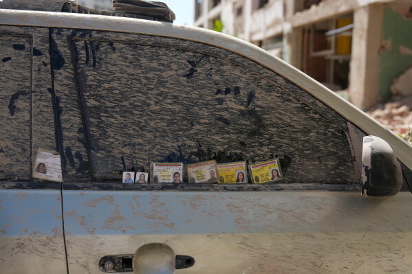 Identification cards and photographs of missing people are left on the window of a dirt-covered car by relatives searching for information in Catia La Mar, Venezuela, Saturday, June 27, 2026, three days after twin earthquakes struck the country. (AP Photo/Fernando Vergara)