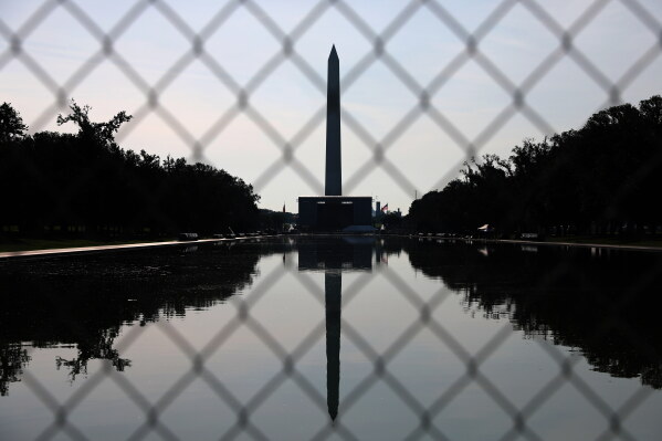 The Washington Monument, reflected in the Lincoln Memorial Reflecting Pool, is seen behind fencing, Tuesday, June 30, 2026, in Washington. (AP Photo/Rahmat Gul)