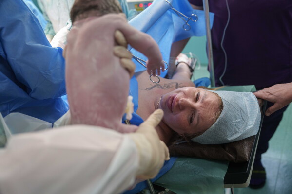 A doctor shows Olha Karpenko her newborn daughter, Diana, for the first time after her birth by cesarean section at the regional perinatal center of Zaporizhzhia, Ukraine, Wednesday, May 6, 2026. (AP Photo/Evgeniy Maloletka)