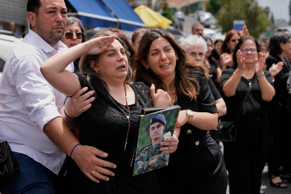 Rozette, second left, the wife of Lebanese army captain Elie Khoury, who was killed on Saturday in an Israeli airstrike, salutes during his funeral procession in Kfar Jarra, southern Lebanon, Monday, June 8, 2026. (AP Photo/Mohammed Zaatari)