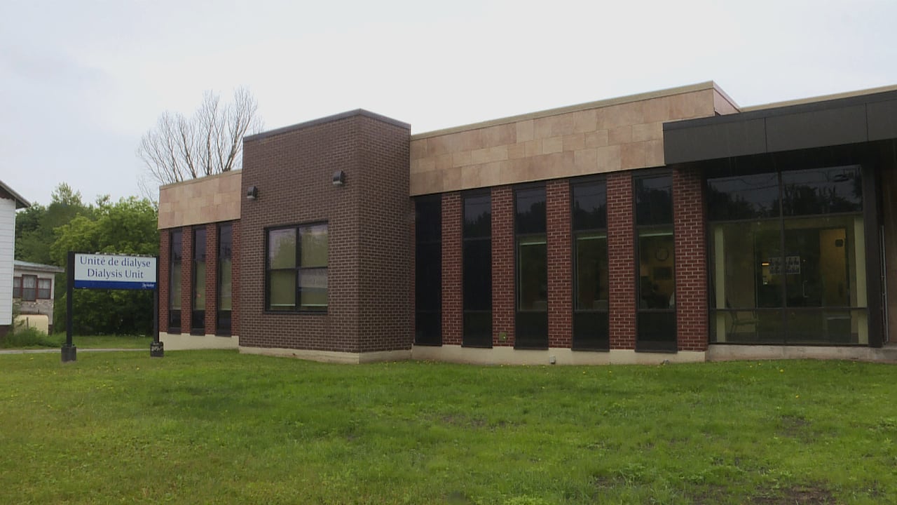 A single-story brick building with several windows and green grass in front, as well as a sign that says "Dialysis Unit"