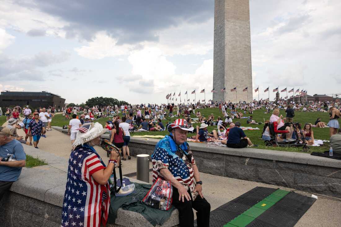People sit near the Washington Monument ahead of the "Salute to America 250" rally on the National Mall during a celebration of America's 250th Independence Day on July 4, 2026 in Washington, DC.