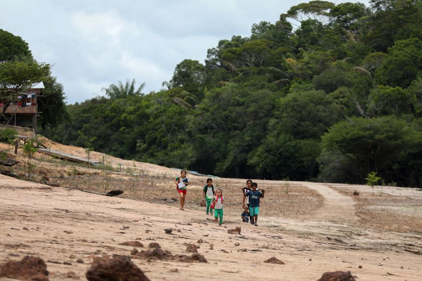 Children walk on a sandbank in Novo Airao, Amazonas state, northern Brazil, on October 1, 2024. An El Niño-fueled drought pushed several tributaries of the Amazon River to critical lows in 2024.