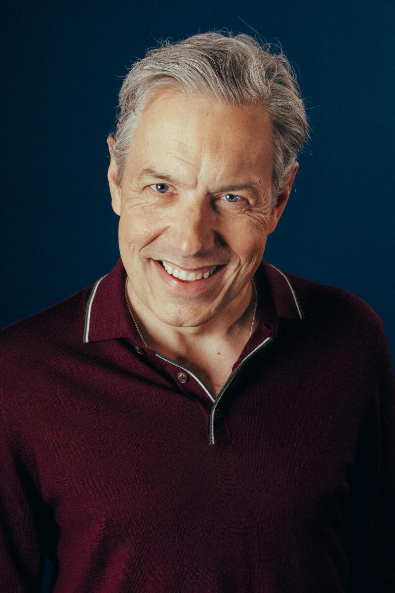 A grinning man in a maroon shirt.