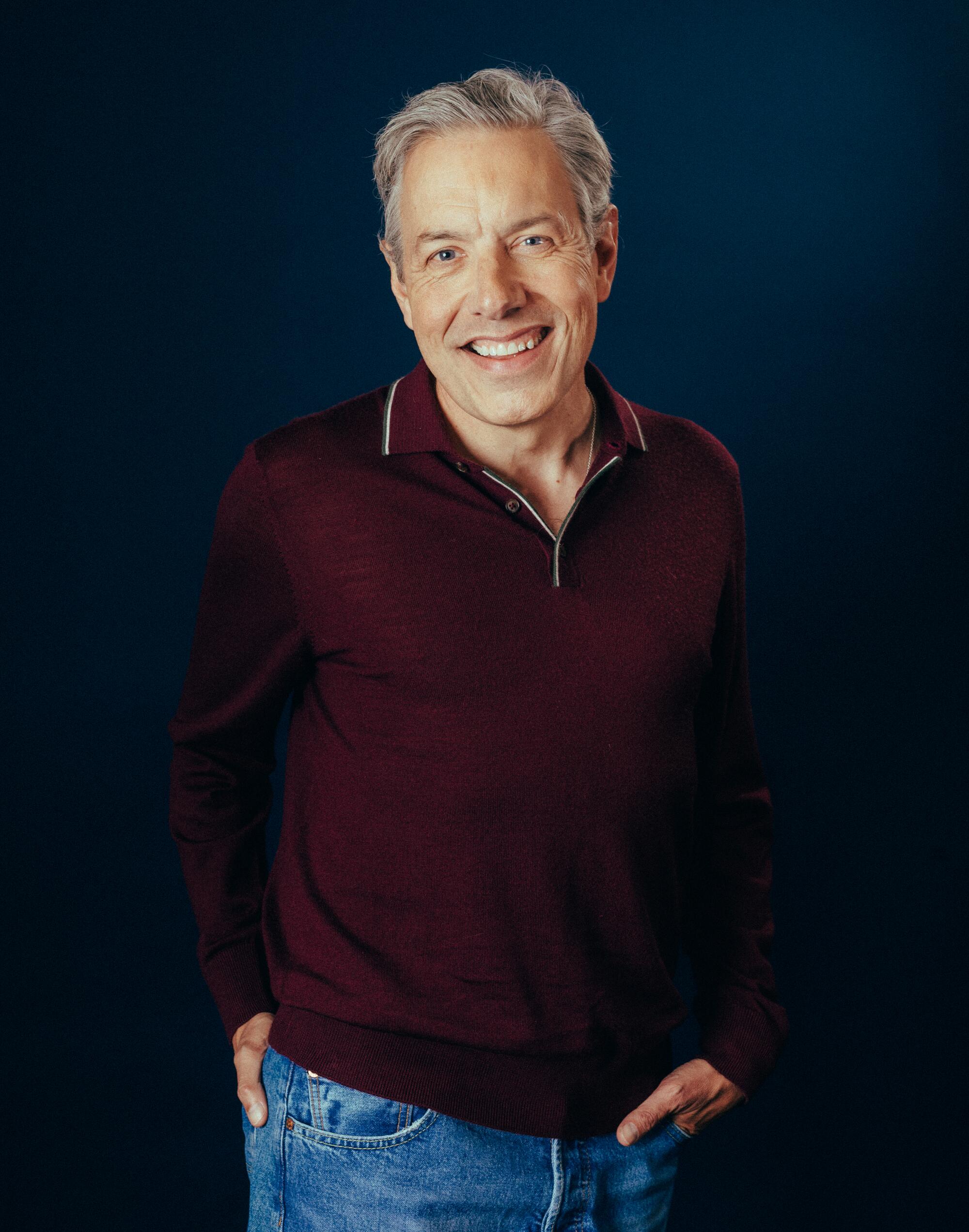 A smiling man with graying hair in a maroon long-sleeve shirt.