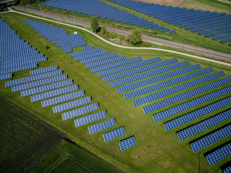 Rows of hundreds of solar panels on green fields.