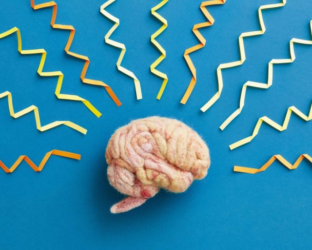 A human brain made of wool with folded paper brainwaves - stock photo