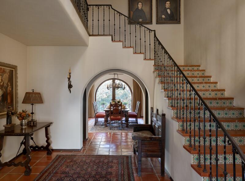 Arches lead toward the dining room with a tiled staircase in the entryway.