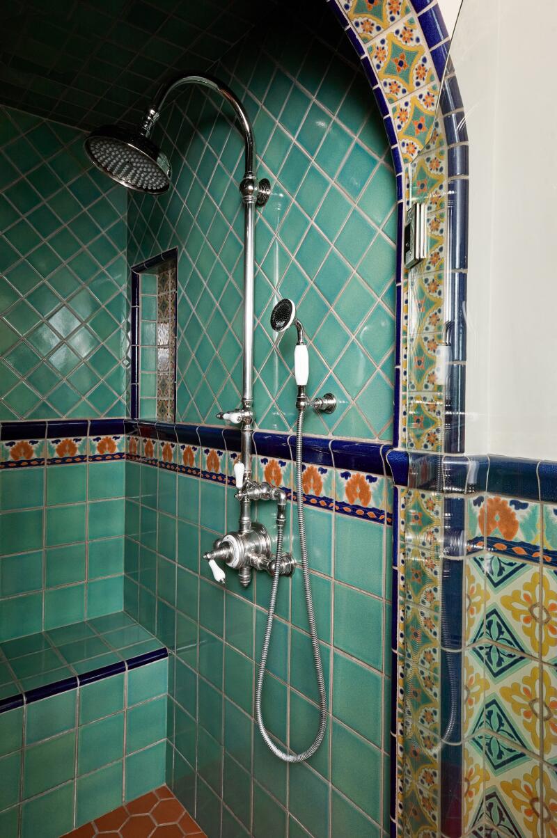 Teal tile in the shower, bordered by yellow and teal tile. 