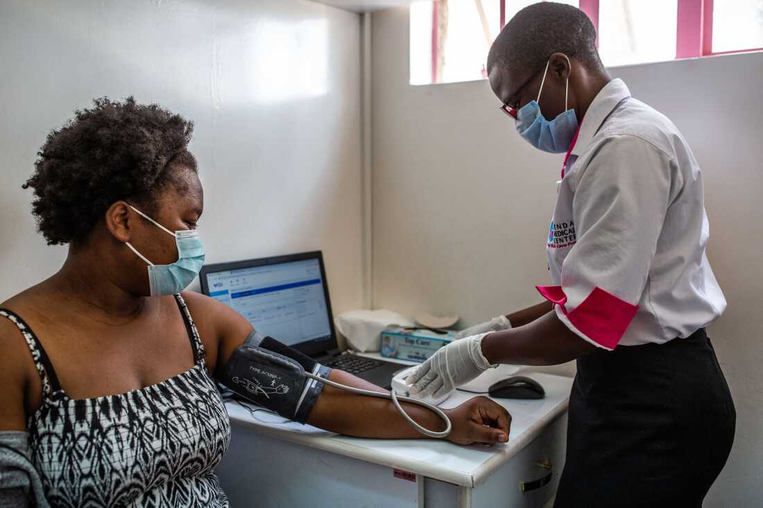 A health worker measures the blood pressure of a woman at Penda Health Clinic Umoja II in Nairobi, Kenya, where researchers have tested an AI tool that can check out the notes taken by clinicians.