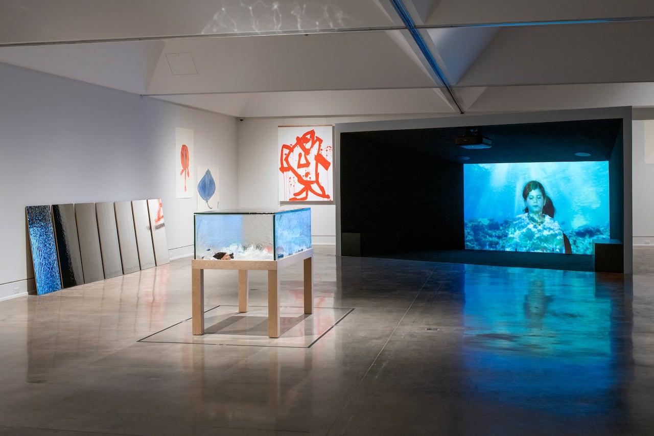 Multiple paintings and projection screens in an art gallery.
