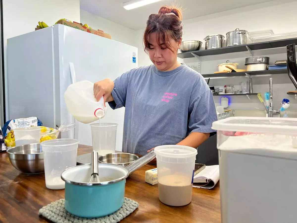 Pastry chef Amanda Tabadero pours milk into a plastic container while preparing ingredients for maritozzi at Creature Coffeeshop in Kaneʻohe, Hawaii, Tuesday, July 7, 2026. (Hikari Mae Hida/Honolulu Civil Beat via AP)