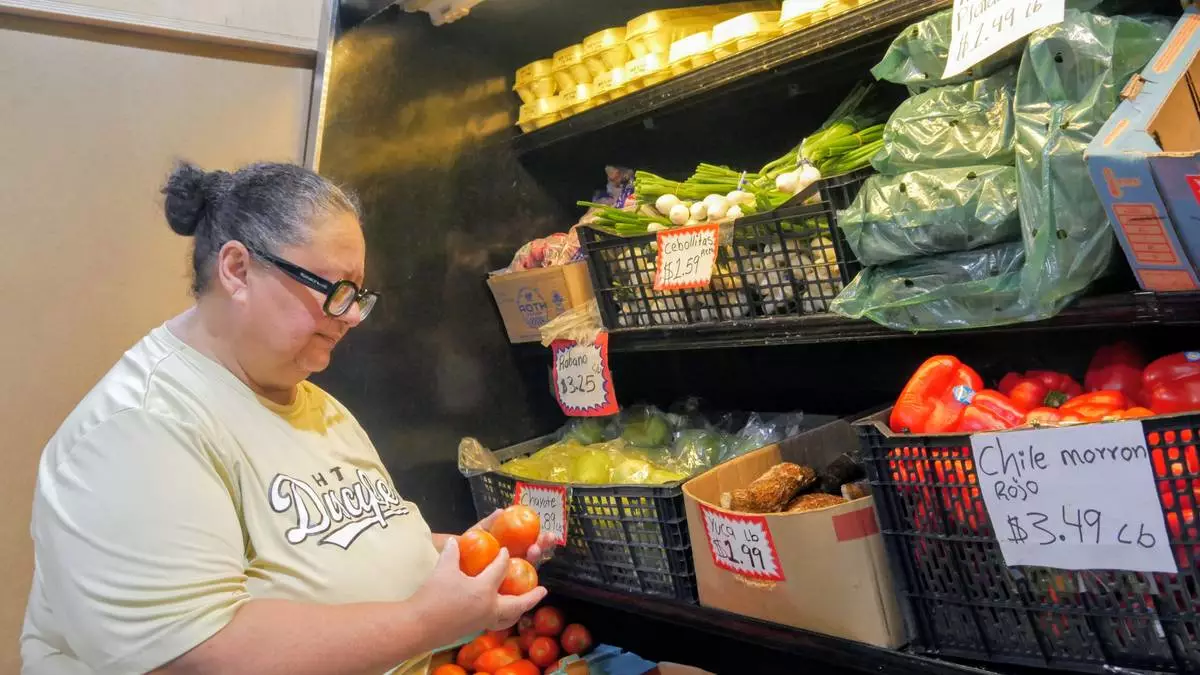 Ada Torres holds tomatoes while shopping for produce, Thursday, July 2, 2026, in Cleveland, Texas, about 45 miles northeast of Houston. (Sandy Guatibonza/La Esquina TX via AP)