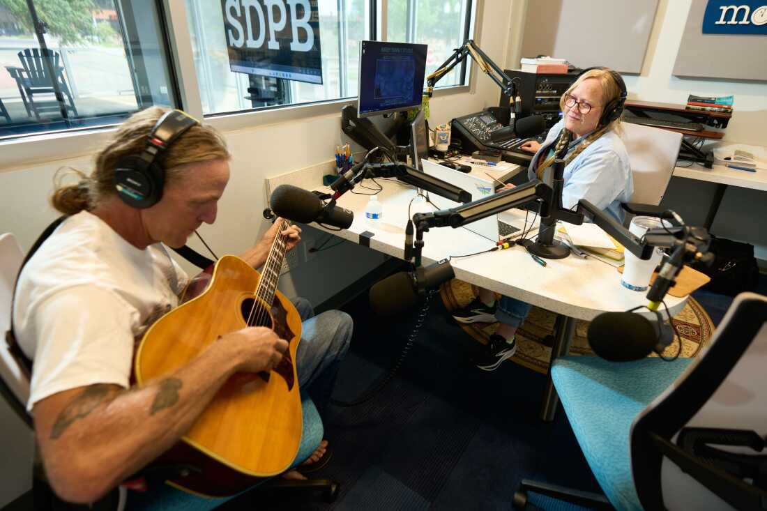 Walsh conducts an interview with musician Matt Fockler, as he plays an acoustic guitar.