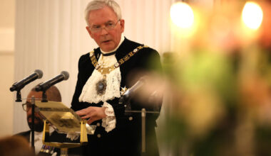 Nicholas Lyons, former Lord Mayor of London, speaking at a podium with microphones, discussing fresh ISA rules.