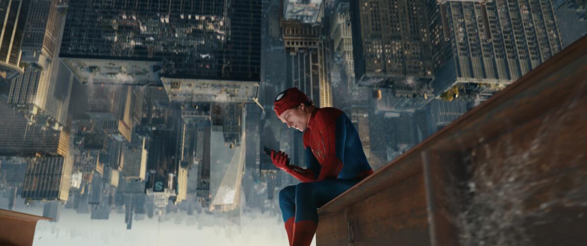 Tom Holland as Spider-Man sits upside down on a beam over a city skyline.