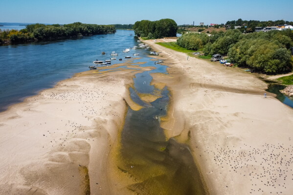 A usually submerged patch of land rises from the surface of the Danube River due to low levels of the water following an extended period of drought in Corabia, Romania, July 29, 2026. (AP Photo/ Nicolae Dumitrache, File)