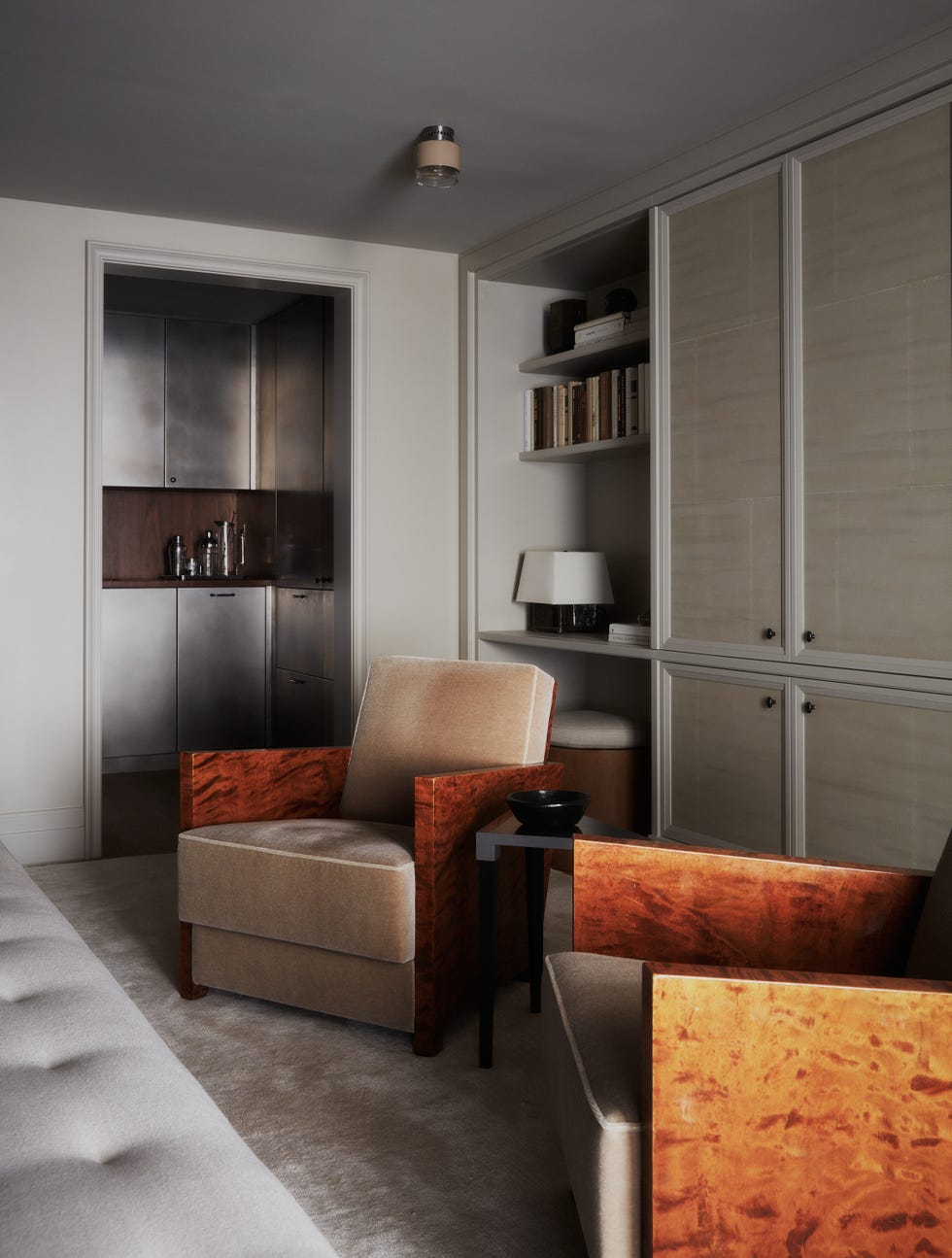 Modern living room featuring two stylish chairs, a small side table, and a glimpse of a kitchenette.