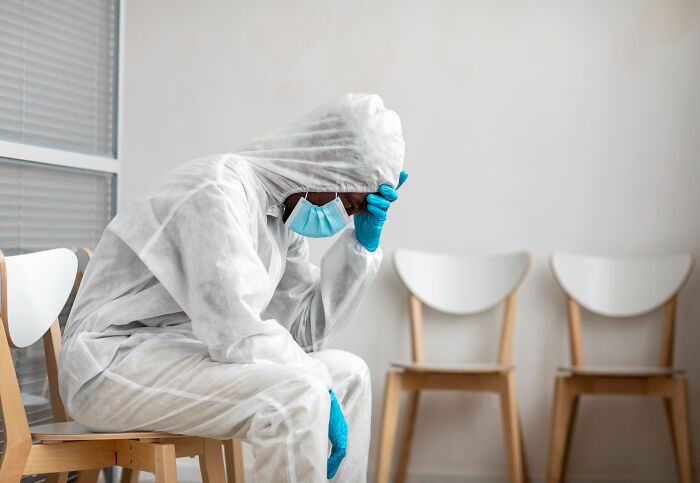 A healthcare worker in a full protective suit and face mask sits, embodying truths about the medical industry.
