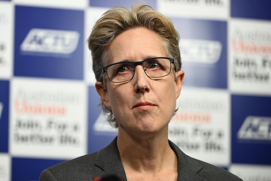 Sally McManus standing in front of an ACTU banner.