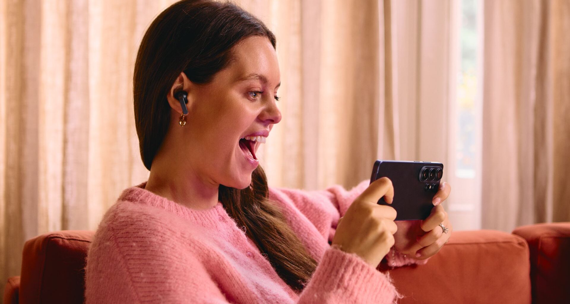 A woman using a Samsung Galaxy S26 Ultra and smiling.