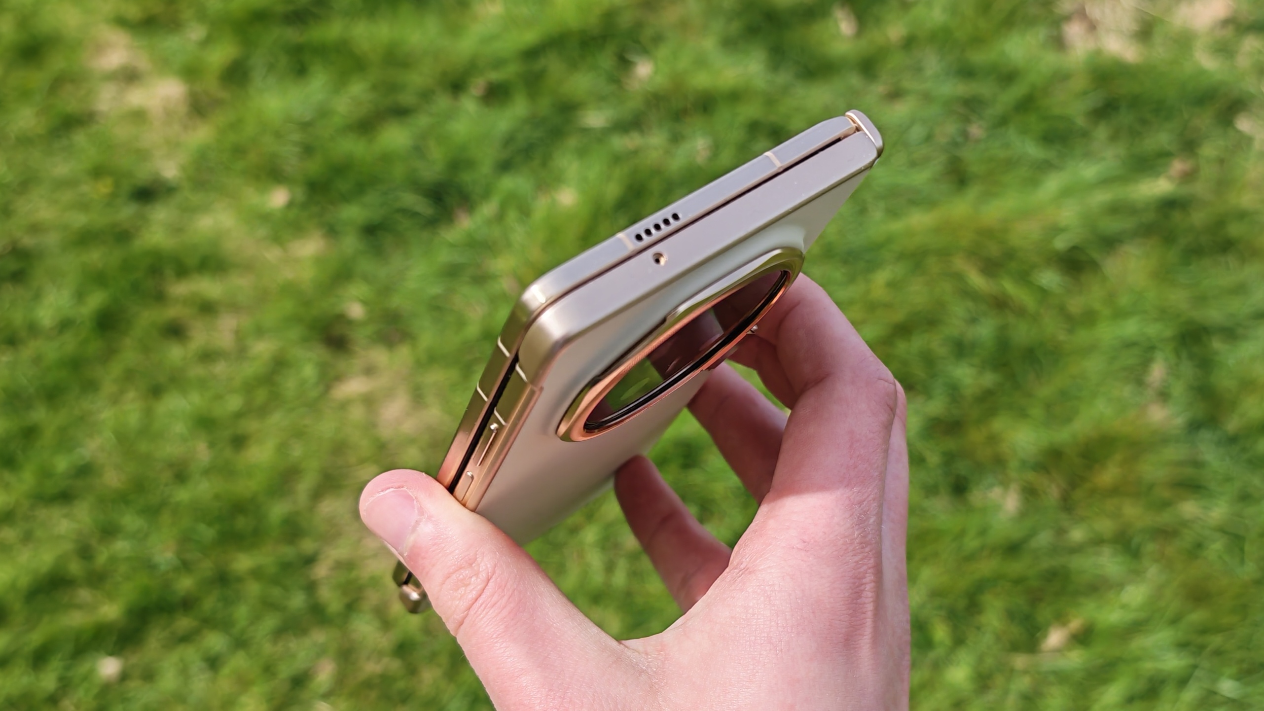The Honor Magic V6 being held in a sunny field.