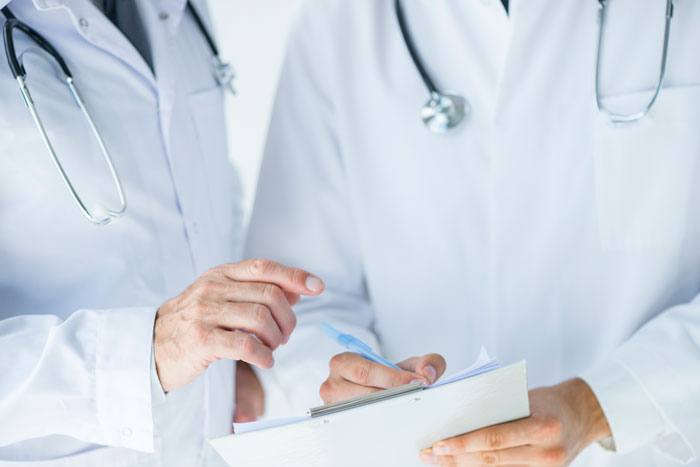 Medical workers in white coats and stethoscopes discussing patient charts, showing the dedicated side of hospitals.