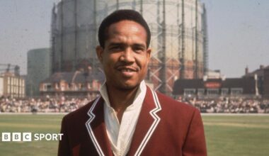 Gary Sobers before the start of the fifth Test between the West Indies and England at the Oval in 1966, standing on the outfield in a claret blazer over his whites, with the nearby gasometer in the background
