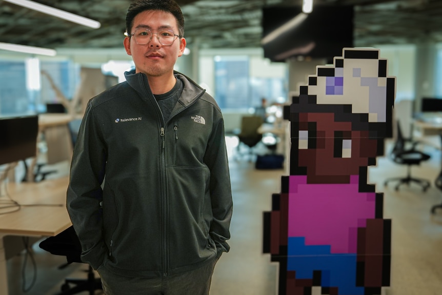 A man stands in front of a computer