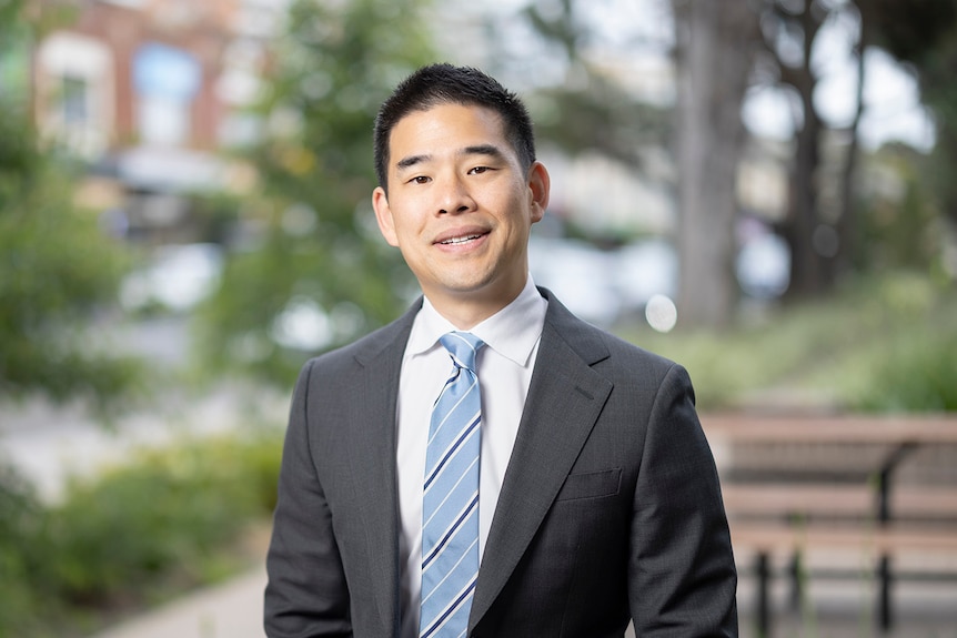 Jeremy Ong in a grey suit and blue tie, smiling outside.
