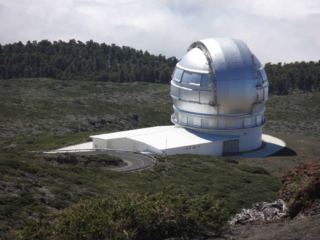 Large astronomical observatory telescope in a mountainous landscape.