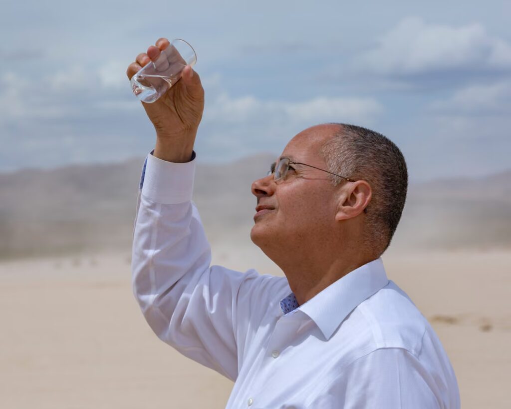 Researcher holding up a flask containing water pulled from air using a prototype. Omar Yaghi