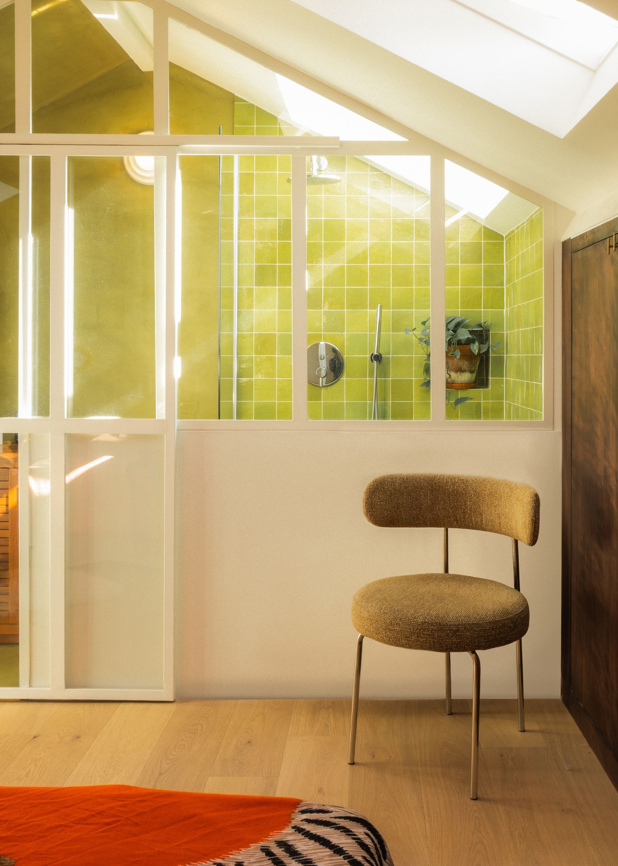 A bedroom with wooden flooring and green tiled bathroom