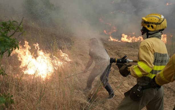 A resident helps firefighters battle a wildfire in Cebreros, near Avila, 80 km west of Madrid on 24 July, 2026.